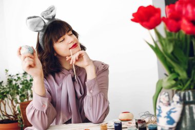 Mutlu Paskalya kavramı. gülümseyen ve laleler ve metin için yer ile ev boya ile rustik tabloda Paskalya yumurtaları boya tavşan kulakları güzel şık kız. kadın rahatlatıcı. Paskalya AVI