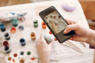 telefon ve Paskalya resmini alarak düz holding eller ile renkli yumurta ve masanın üzerine boya. Mutlu Paskalya kavramı. instagram ve bloglama fotoğraf kavramı