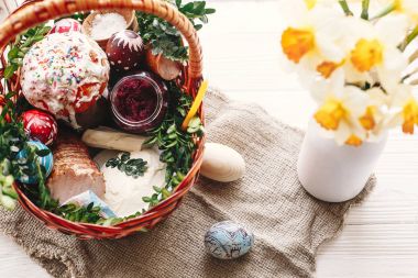 boyalı yumurta, ekmek, jambon, pancar, şık sepetle tereyağı görünümü bahar çiçek ve mum ile rustik ahşap arka plan üzerinde top. nimet Kilisesi Paskalya gıda. Mutlu Paskalya kavramı