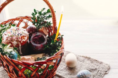 Mutlu Paskalya kavramı. boyalı yumurta, ekmek, jambon, pancar, şık sepetle rustik ahşap arka plan bahar çiçek ve mum üzerine tereyağı. nimet Kilisesi Paskalya yemek.