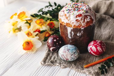 şık boyalı Paskalya yumurtaları ve Paskalya kek üzerine beyaz rustik ahşap arka plan bahar çiçek ve mum ile. mevsim Selam. metin için yer. Modern mutlu Paskalya görüntü