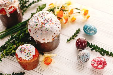 boyalı yumurta ve Paskalya kek üzerinde beyaz ahşap arka plan bahar çiçekleri ile renk