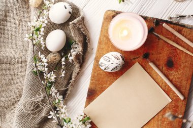 rustik ahşap arka plan bahar çiçek ve mum ile şık boyalı Paskalya yortusu yumurta siyah ve beyaz renklere. Mutlu Paskalya tebrik kartı. Modern Paskalya yumurtaları görünümü top. tatil gelenekleri