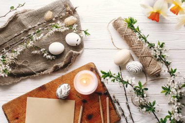 şık Paskalya düz yatıyordu. Paskalya yumurtaları rustik ahşap arka plan bahar çiçek ve mum ile siyah ve beyaz renklere boyanmış. Mutlu Paskalya tebrik kartı. Modern Paskalya yumurtaları görünümü top.