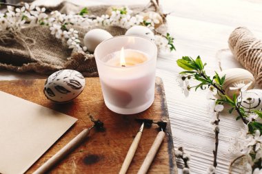 rustik ahşap arka plan bahar çiçek ve mum ile şık boyalı Paskalya yortusu yumurta siyah ve beyaz renklere. Mutlu Paskalya tebrik kartı. Modern Paskalya yumurtaları. tatil gelenekleri