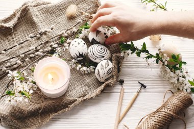 şık tutan el Paskalya yortusu yumurta çiçeklerle rustik ahşap arka plan, boyalı. Modern Paskalya yumurtaları görünümü top. balmumu ve mum ile boyanmış. tatil gelenekleri. Mutlu Paskalya AVI