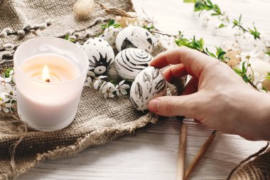 şık tutan el Paskalya yortusu yumurta çiçeklerle rustik ahşap arka plan, boyalı. Modern Paskalya yumurtaları görünümü top. balmumu ve mum ile boyanmış. tatil gelenekleri. Mutlu Paskalya AVI
