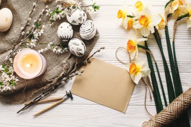 rustik ahşap arka plan bahar çiçek ve mum ile şık boyalı Paskalya yortusu yumurta siyah ve beyaz renklere. Mutlu Paskalya tebrik kartı. Modern Paskalya yumurtaları görünümü top. tatil gelenekleri