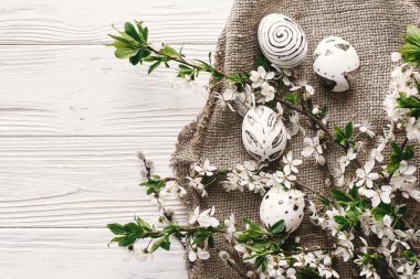 boyalı yumurta siyah ve beyaz renklere rustik ahşap arka plan bahar çiçekleri ile şık Paskalya düz yatırın. Mutlu Paskalya tebrik kartı, metin için yer. Modern Paskalya yumurtaları