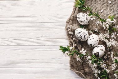 boyalı yumurta siyah ve beyaz renklere rustik ahşap arka plan bahar çiçekleri ile şık Paskalya düz yatırın. Mutlu Paskalya tebrik kartı, metin için yer. Modern Paskalya yumurtaları