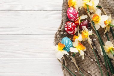 rustik ahşap arka plan bahar çiçekleri ve Söğüt dalları üzerinde şık boyalı Paskalya yumurta. Mutlu Paskalya tebrik kartı düz yatıyordu. metin için yer. Modern renkli Paskalya yumurtaları