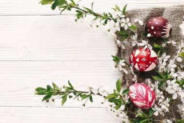 şık Paskalya düz yatıyordu. boyalı yumurta rustik ahşap arka plan bahar çiçekleri ve Söğüt dalları üzerinde. Mutlu Paskalya tebrik kartı. metin için yer. Modern renkli Paskalya yumurtaları