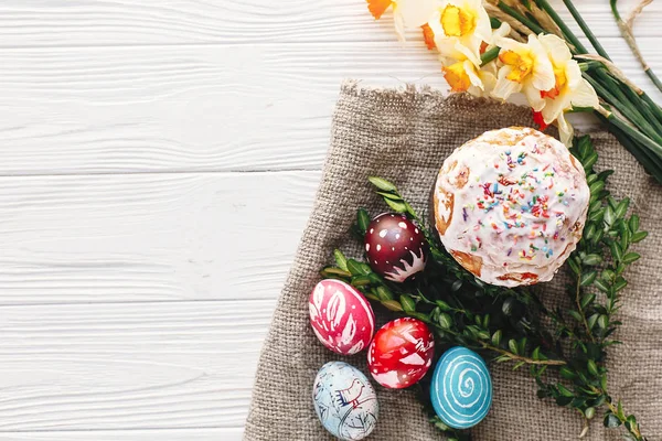 şık boyalı yumurta ve Paskalya kek rustik ahşap arka plan bahar çiçekleri ve mum, üstten görünüm üzerinde. metin için yer. Mutlu Paskalya kavramı, düz yatıyordu. mevsim Selam
