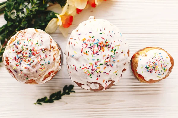 bahar çiçekleri, üstten görünüm ile beyaz rustik ahşap arka plan üzerinde renkli buzlanma ile lezzetli Paskalya kek. metin için yer. Mutlu Paskalya kavramı, düz yatıyordu. mevsim Selam