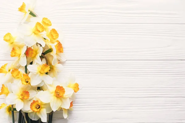 白い木製の背景の美しい新鮮な水仙平面図です フラット スペースと素朴な木の明るい黄色の花とこんにちはに春の画像を置きます 花のグリーティング カード — ストック写真