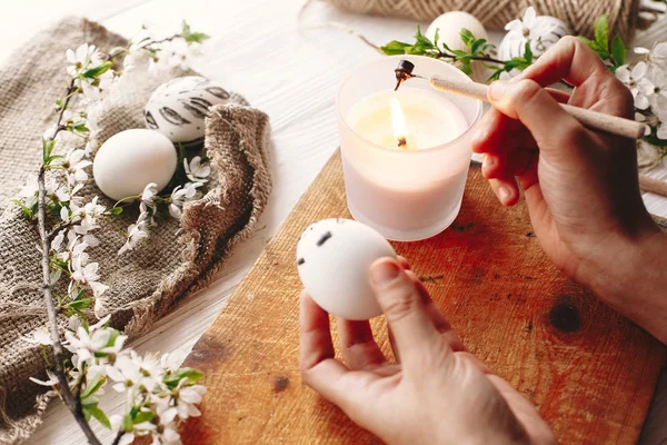 el Holding ve Paskalya yumurtası, çiçekli ahşap arka plan boyama. Şık modern Paskalya yumurtaları. balmumu ve mum boyama. tatil gelenekleri. rustik görüntüsü