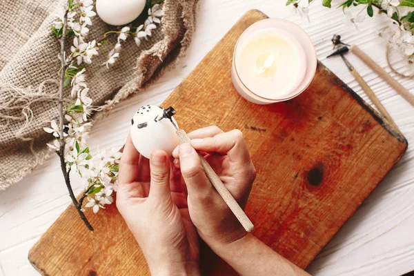 el Holding ve Paskalya yumurtası, çiçekli ahşap arka plan boyama. Şık modern Paskalya yumurtaları. balmumu ve mum boyama. tatil gelenekleri. rustik görüntüsü. Üstten Görünüm