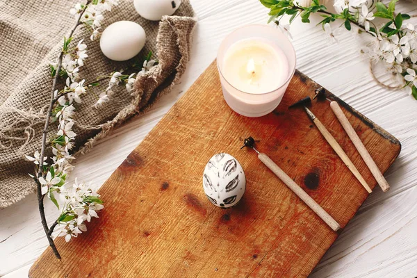 rustik ahşap arka plan bahar çiçek ve mum ile şık boyalı Paskalya yortusu yumurta siyah ve beyaz renklere. Modern Paskalya yumurtaları görünümü top. tatil gelenekleri. Mutlu Paskalya AVI