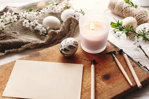rustik ahşap arka plan bahar çiçek ve mum ile şık boyalı Paskalya yortusu yumurta siyah ve beyaz renklere. Mutlu Paskalya tebrik kartı. Modern Paskalya yumurtaları görünümü top. tatil gelenekleri