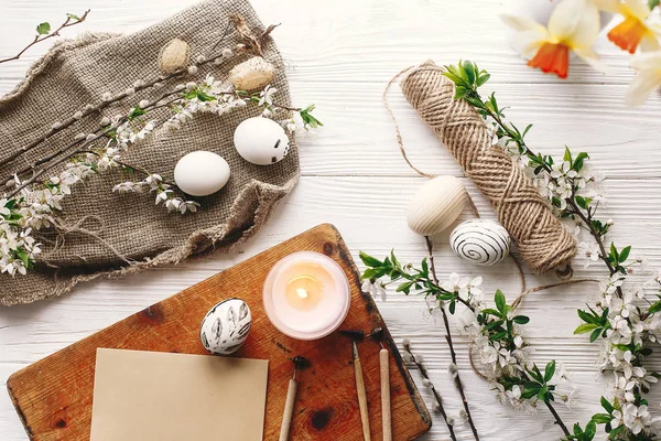 şık Paskalya düz yatıyordu. Paskalya yumurtaları rustik ahşap arka plan bahar çiçek ve mum ile siyah ve beyaz renklere boyanmış. Mutlu Paskalya tebrik kartı. Modern Paskalya yumurtaları görünümü top.