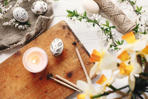春の花とキャンドルで素朴な木製の背景でスタイリッシュな塗られたイースターエッグ黒と白の色 モダンなイースターエッグ平面図です 休日の伝統 幸せなイースター ハント — ストック写真