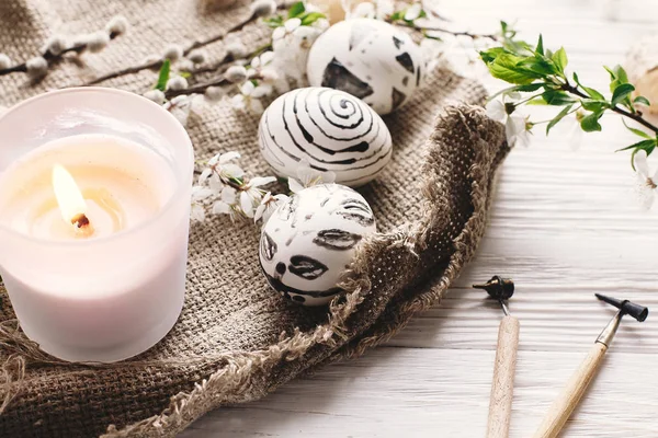 rustik ahşap arka plan bahar çiçek ve mum ile şık boyalı Paskalya yortusu yumurta siyah ve beyaz renklere. Mutlu Paskalya tebrik kartı. Modern Paskalya yumurtaları görünümü top. tatil gelenekleri