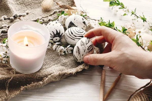 şık tutan el Paskalya yortusu yumurta çiçeklerle rustik ahşap arka plan, boyalı. Modern Paskalya yumurtaları görünümü top. balmumu ve mum ile boyanmış. tatil gelenekleri. Mutlu Paskalya AVI