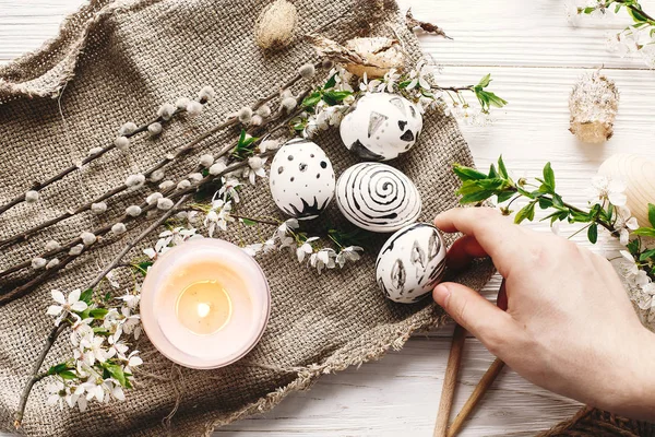 şık tutan el Paskalya yortusu yumurta çiçeklerle rustik ahşap arka plan, boyalı. Modern Paskalya yumurtaları görünümü top. balmumu ve mum ile boyanmış. tatil gelenekleri. Mutlu Paskalya AVI