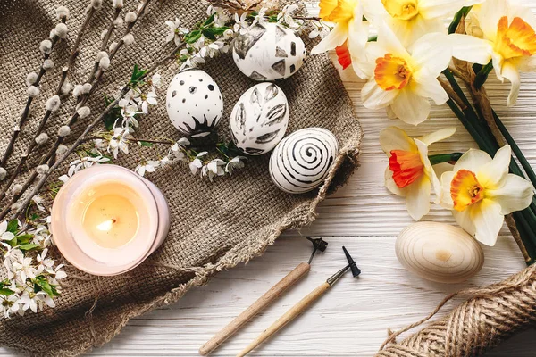 şık Paskalya düz yatıyordu. Paskalya yumurtaları rustik ahşap arka plan bahar çiçek ve mum ile siyah ve beyaz renklere boyanmış. Mutlu Paskalya tebrik kartı. Modern Paskalya yumurtaları görünümü top.
