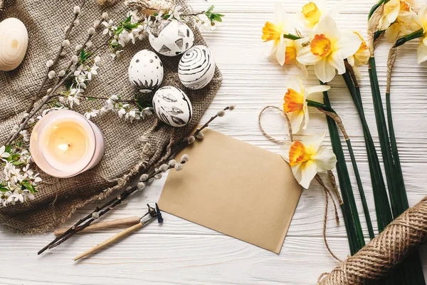 rustik ahşap arka plan bahar çiçek ve mum ile şık boyalı Paskalya yortusu yumurta siyah ve beyaz renklere. Mutlu Paskalya tebrik kartı. Modern Paskalya yumurtaları görünümü top. tatil gelenekleri