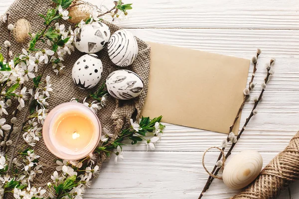rustik ahşap arka plan bahar çiçek ve mum ile şık boyalı Paskalya yortusu yumurta siyah ve beyaz renklere. Mutlu Paskalya tebrik kartı. Modern Paskalya yumurtaları görünümü top. tatil gelenekleri