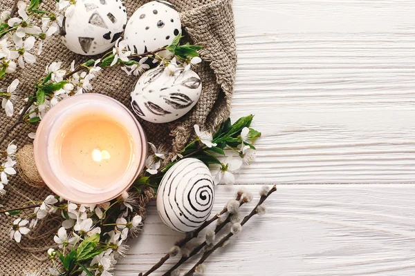 şık Paskalya düz yatıyordu. Paskalya yumurtaları rustik ahşap arka plan bahar çiçek ve mum ile siyah ve beyaz renklere boyanmış. Mutlu Paskalya tebrik kartı. Modern Paskalya yumurtaları görünümü top.