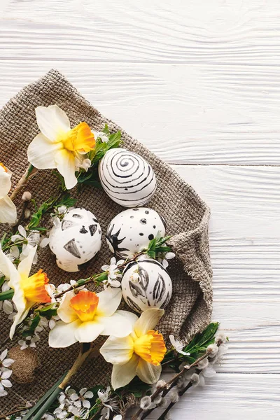şık Paskalya düz yatıyordu. Paskalya yumurtaları rustik ahşap arka plan bahar çiçekleri ile siyah ve beyaz renklere boyanmış. Mutlu Paskalya tebrik kartı. Modern Paskalya yumurtaları görünümü top. Dikey görüntü