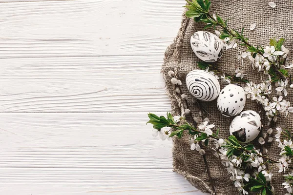 boyalı yumurta siyah ve beyaz renklere rustik ahşap arka plan bahar çiçekleri ile şık Paskalya düz yatırın. Mutlu Paskalya tebrik kartı, metin için yer. Modern Paskalya yumurtaları