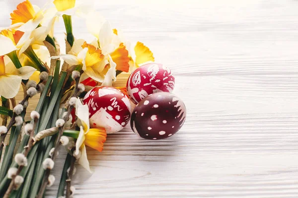 Mutlu Paskalya kavramı. rustik ahşap arka plan bahar çiçekleri ve Söğüt dalları ile şık boyalı yumurta. mevsim tebrik kartı. metin için yer. Modern renkli Paskalya yumurtaları