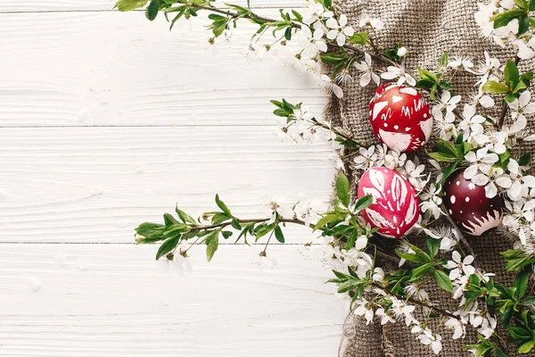 rustik ahşap arka plan bahar çiçekleri ve Söğüt dalları üzerinde şık boyalı Paskalya yumurta. Mutlu Paskalya tebrik kartı düz yatıyordu. metin için yer. Modern renkli Paskalya yumurtaları