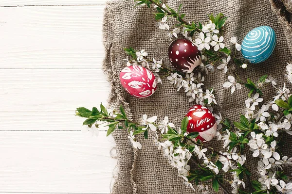 rustik ahşap arka plan bahar çiçekleri ve Söğüt dalları üzerinde şık boyalı Paskalya yumurta. Mutlu Paskalya tebrik kartı düz yatıyordu. metin için yer. Modern renkli Paskalya yumurtaları