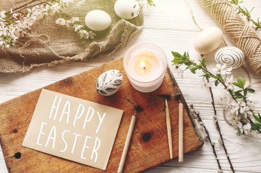 Mutlu Paskalya metin. dilekler kartı. rustik ahşap arka plan bahar çiçek ve mum ile şık boyalı Paskalya yumurtası. Modern üstten görünüm. gelenekleri