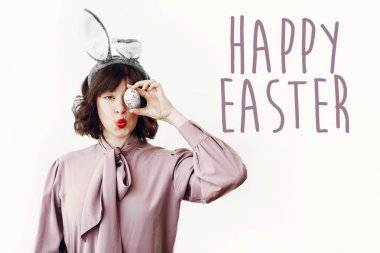 Mutlu Paskalya metin. dilekler kartı. Beyaz arka plan üzerinde renkli Paskalya yortusu yumurta tutarak ve gülümseyen tavşan kulakları güzel mutlu kızı. Paskalya AVI kavramı. komik an