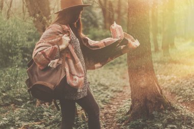 harika akşam güneş ışık ormanda keşfetmek sırt çantası ile şapkalı şık Gezgin kız. 