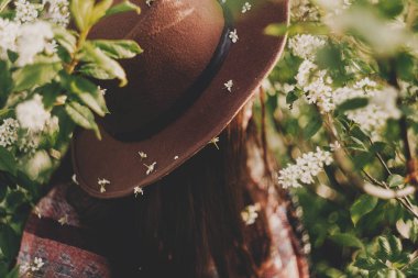 güzel beyaz çiçekler şapka bir hippi kız yeşil yaprakları Akşam güneşiyle bloom ile. şık kadın Gezgin sakin sakin ol bahar bahçe içinde