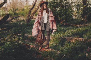 şık hippi kız şapka ve güneş ışığı akşam sırt çantası ormanda rahatlatıcı tutan panço. bohem şık kadın Gezgin güneş ışığı altında. metin için yer. Sakin atmosferik an