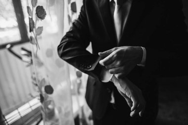 damat takım elbise koyarak. şık adam düğün salonunda sabah hazırlanıyor. siyah ve beyaz