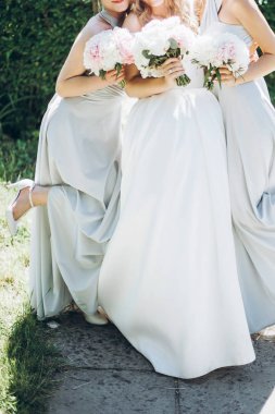 güzel nedime ve şık Şakayık buketleri sabah bahar bahçe içinde tutarak gelin. muhteşem bir kadın inanılmaz ipek güneşli parkta poz Giydir. düğün günü