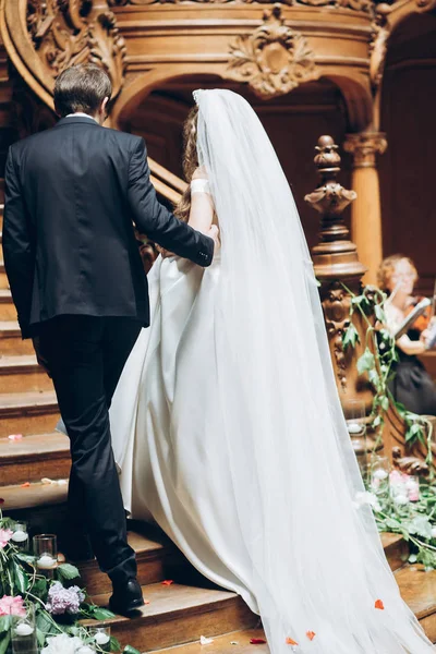 手をつないで 歩いて新郎新婦結婚式屋内で通路をダウンします 古い木製の階段を歩いてください — ストック写真