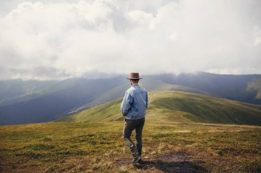 şık seyahat adam şapka ayakta bulutlar güneşli dağların tepesinde. metin için yer. tepelerde seyahat hipster adam. muhteşem atmosferik an. seyahat ve Yolculuk tutkusu kavramı