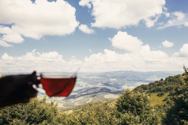 Gezgin penceresinde dağlar ve gökyüzü manzaralı sıcak çay bardak tutan. içki holding ve dağın tepesinde rahatlatıcı bir hipster adam. yaz tatil kavramı. dağda odaklanmak
