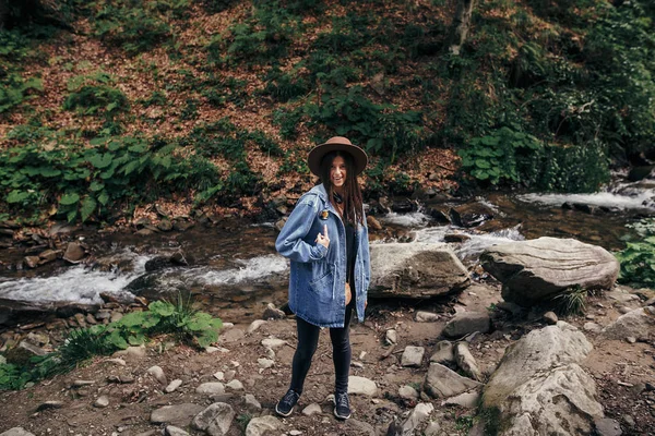 Élégant Voyageur Fille Chapeau Montrant Doigt Rivière Cascade Dans Forêt — Photo