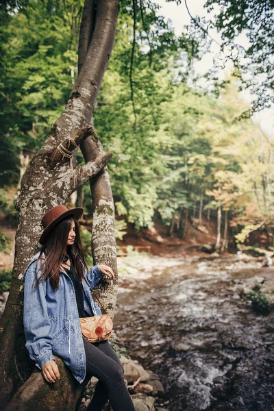 Chica Viajera Con Estilo Sombrero Sentado Árbol Mirando Río Bosque —  Fotos de Stock