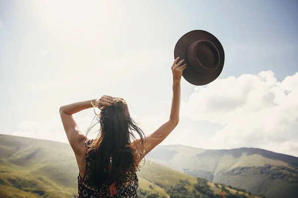 旅行和流浪概念 旅行者时髦的女孩拿着帽子 看着阳光明媚的山脉 文本的空间 惊人的大气时刻 快乐的女人旅行 — 图库照片